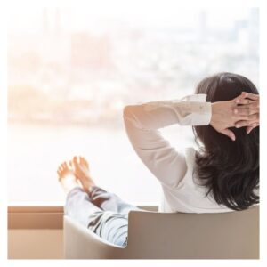 Woman relaxing with feet up and hands behind head looking out a window